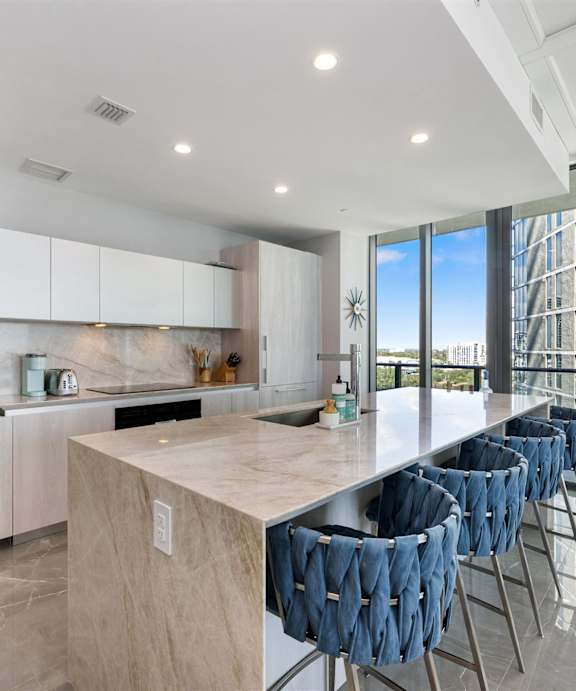 A modern kitchen with a white countertop and wooden cabinets.