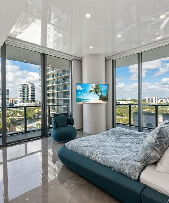 A white bedroom with a bed, nightstand, and a television.