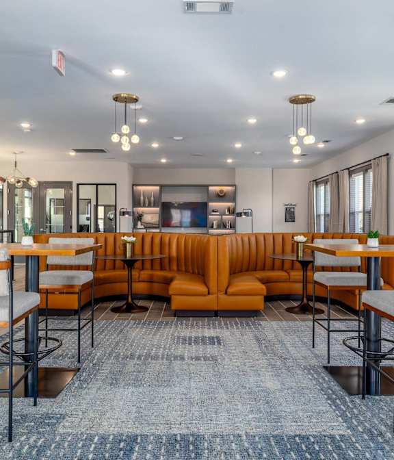 A large room with a long orange couch and a blue rug.