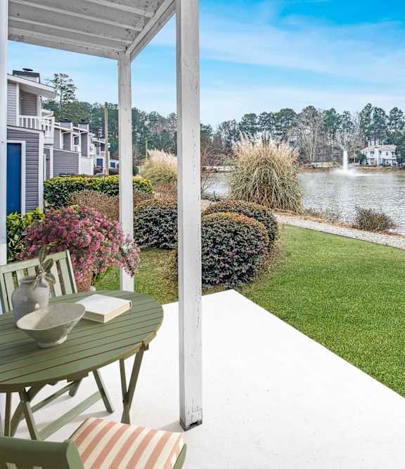 A patio with a table and chairs overlooks a body of water.