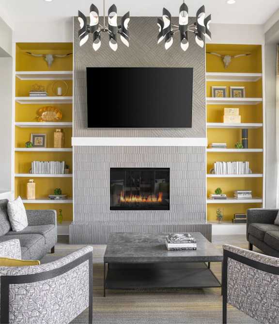 A modern living room with a grey fireplace and a television mounted above it.