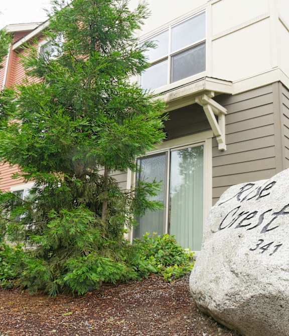A large rock with the words "Cob West 341" written on it in front of a house.
