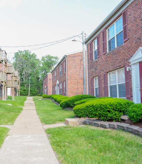 A long concrete walkway leads between two rows of red brick apartment buildings.
