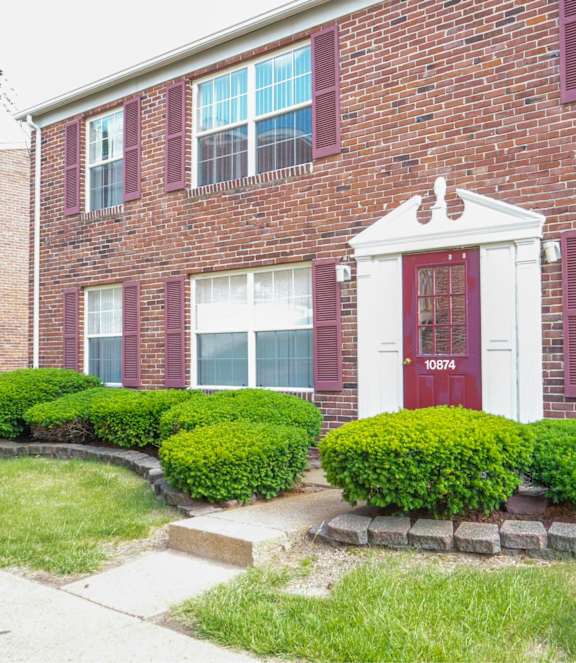 A red brick house with a white door and windows.
