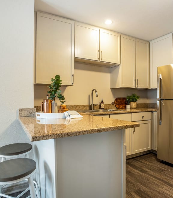 a kitchen with a granite counter top and a stainless steel refrigerator