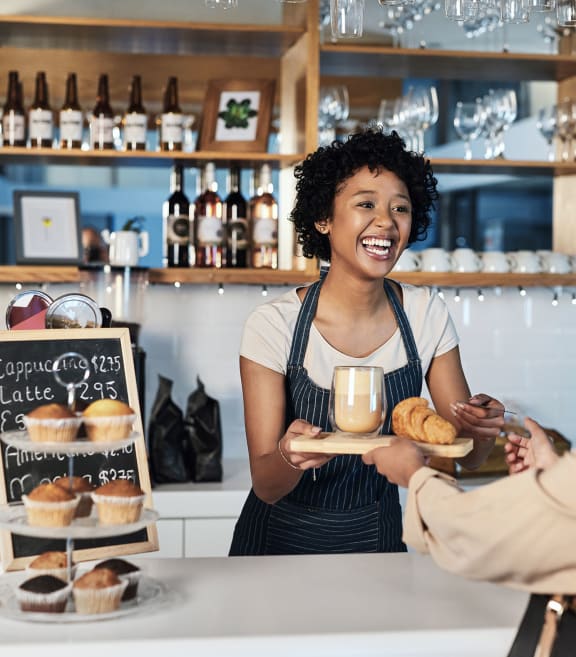 a woman handing a tray of donuts to a customer in a bakery at Willowest in Lindbergh in Atlanta, GA