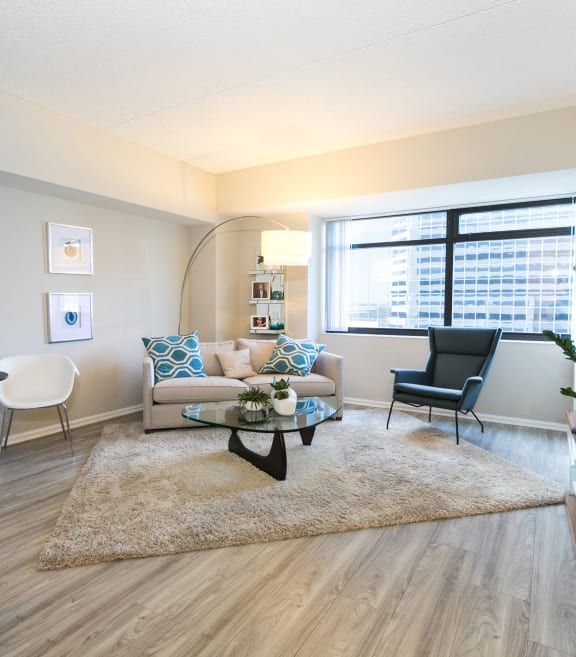 a living room with a couch and a table and a window  at Apartments at Denver Place, Denver Colorado