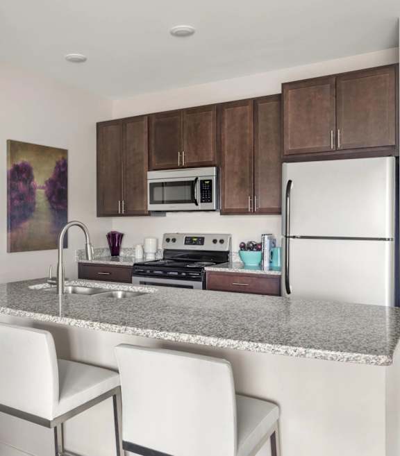 A kitchen with a granite countertop and white chairs.