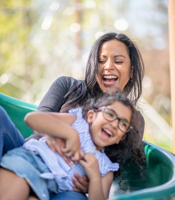 A woman and a child are playing on a slide.