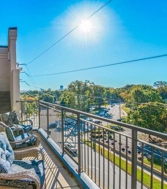 A sunny day on a balcony with a table and chairs.