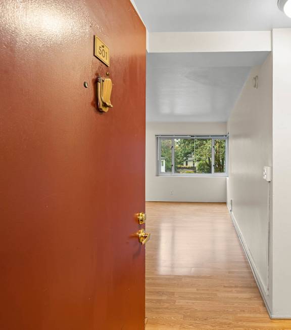 an empty room with a red door and a hallway to a white room