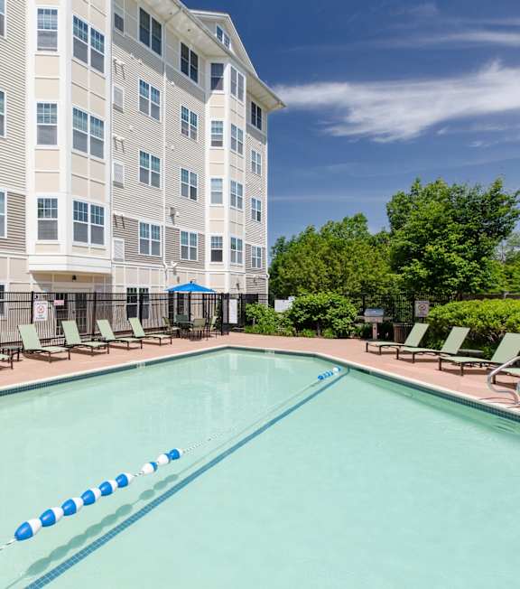 A large swimming pool in front of a multi-story apartment building.