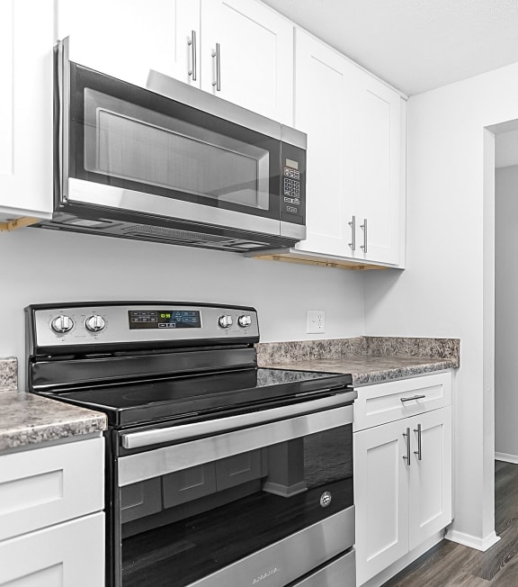 a kitchen with white cabinets and black appliances and a microwave at Gull Harbor Apartments in New London, CT, 06320