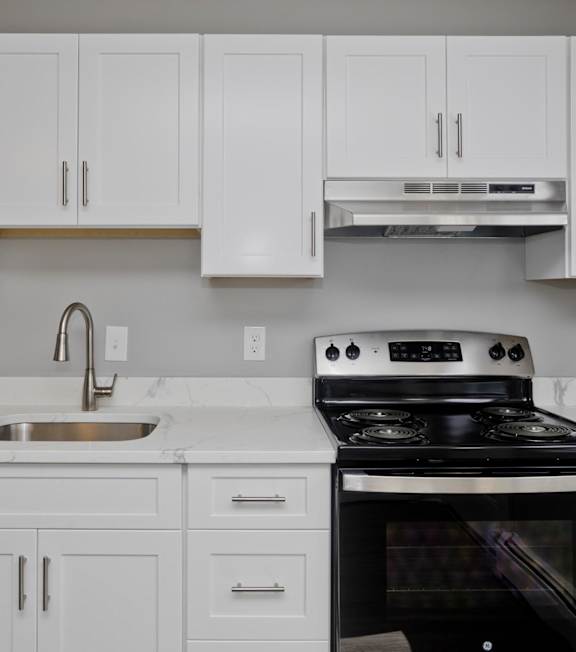 a white kitchen with black appliances and white cabinets at Hawkins Meadow in Amherst, MA, 01002