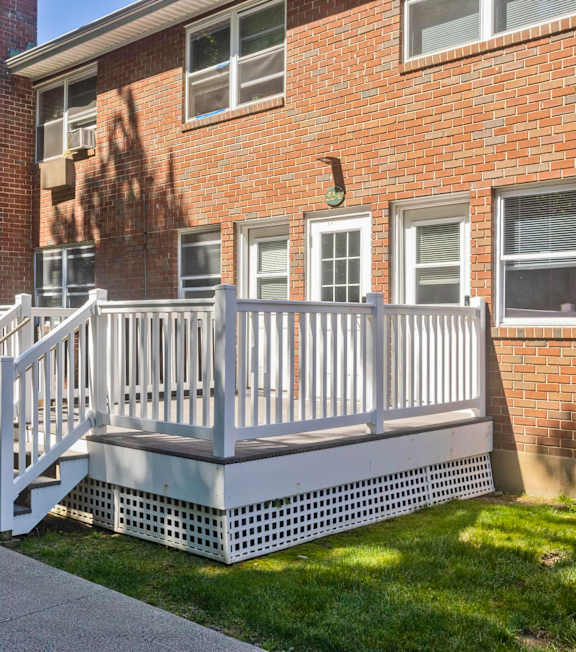 a porch with a white fence in front of a brick building at Hawkins Meadow in Amherst, MA, 01002
