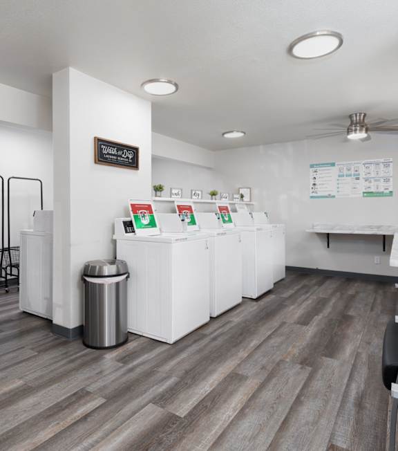 A white reception desk with a trash can and a sign on the wall.