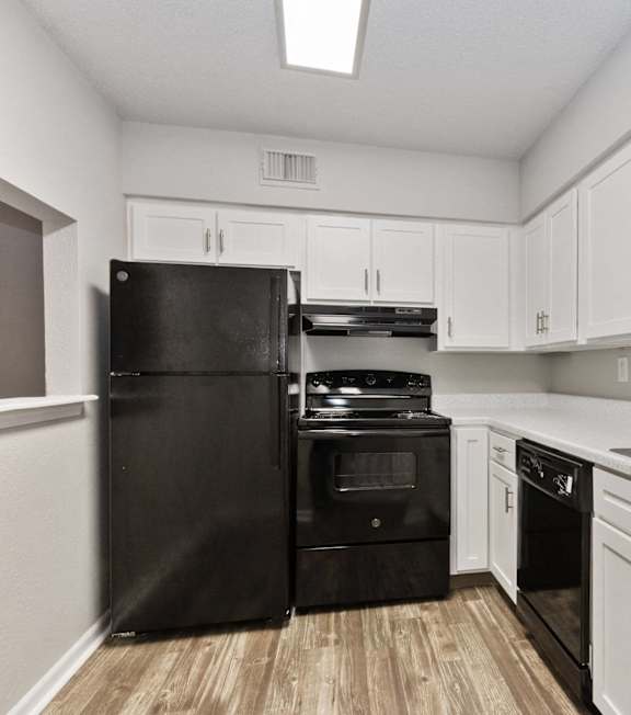 A kitchen with black appliances and white cabinets.