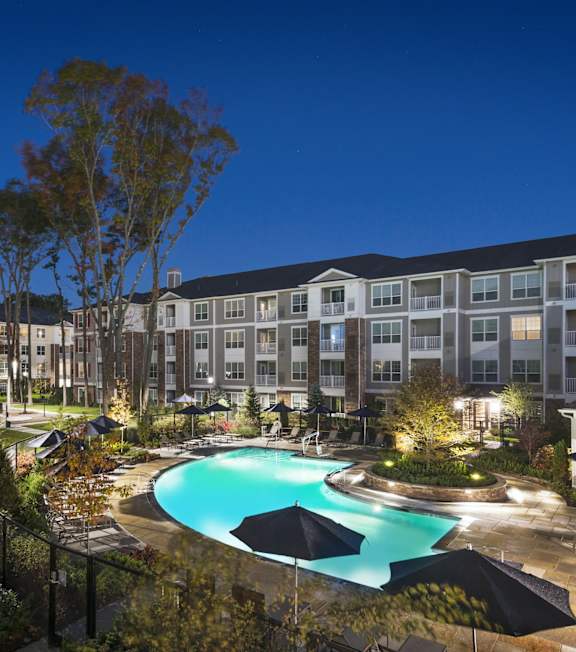 A large apartment complex with a pool and trees.