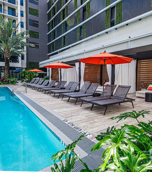A pool area with lounge chairs and umbrellas.