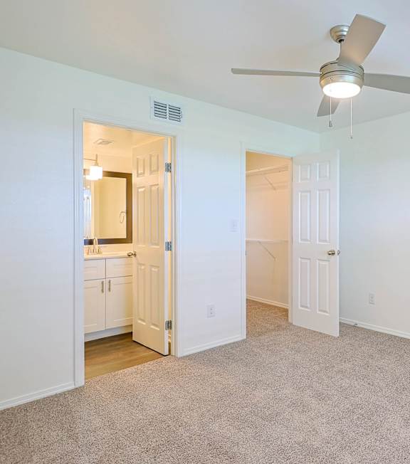 A room with a ceiling fan and carpeted floor.