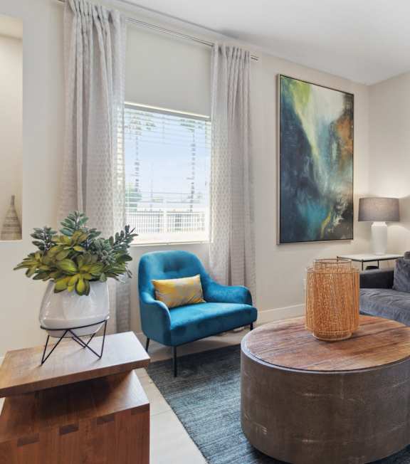 A living room with a grey couch, a blue chair, and two paintings on the wall.