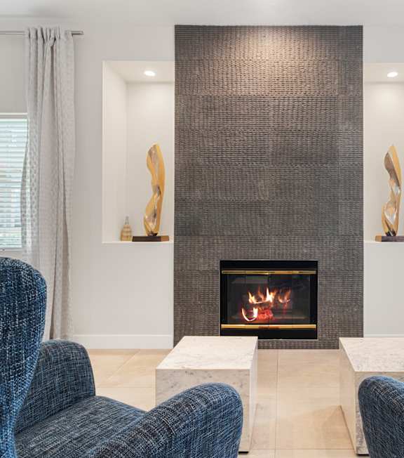A living room with a fireplace and two chairs.