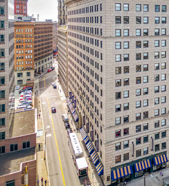 A large building with many windows is in the middle of a city street.
