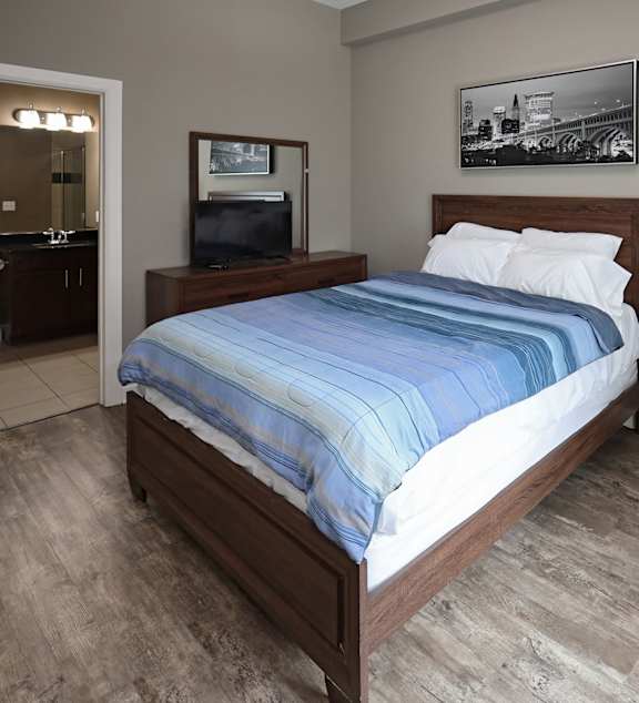 A bedroom with a large bed and a wooden nightstand.