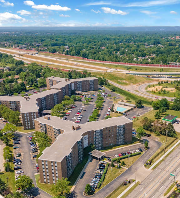 A large building complex is surrounded by a parking lot and a highway.