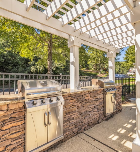 a patio with a barbecue grill and a stone wall and a pergola at Marina Point, Chattanooga Tennessee
