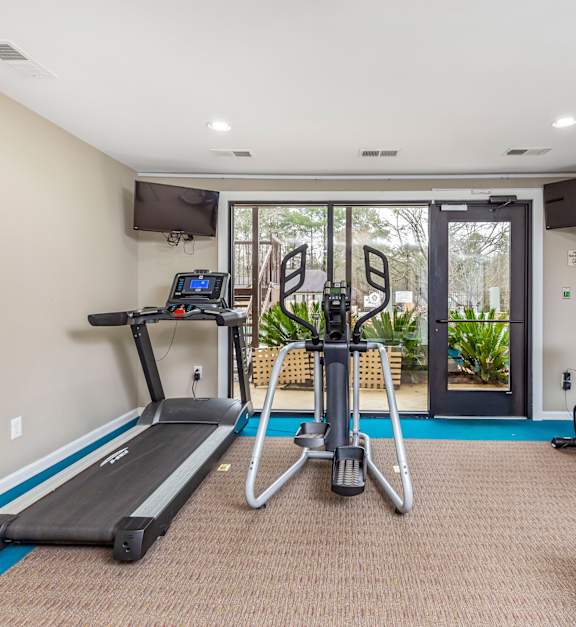 A gym with treadmills, exercise bikes, and a television at The Vistas, Macon, Georgia