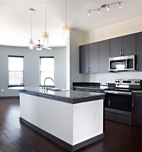 an empty kitchen with an island and black and white at Epic Apartments, Denton