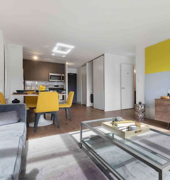 A modern living room with a grey sofa, yellow chairs, and a glass coffee table.