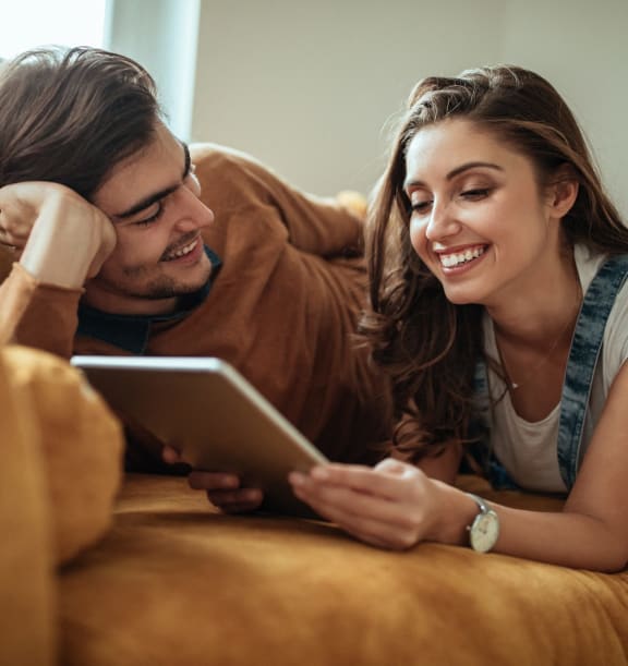 a man and woman laying on a couch looking at a tabletat First Street Lofts in Downtown Bismarck, Bismarck