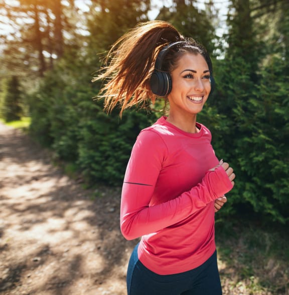 a young woman running while wearing headphones and smiling
