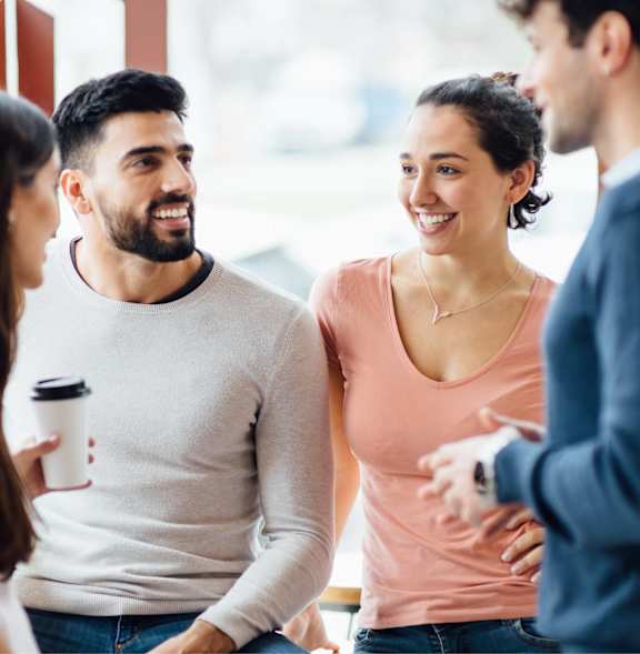 Four people are having a conversation in a brightly lit room.