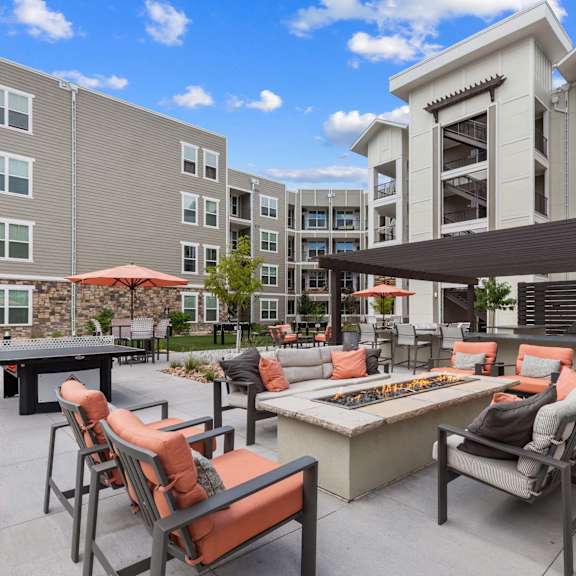 A patio with chairs and a table is surrounded by apartment buildings.