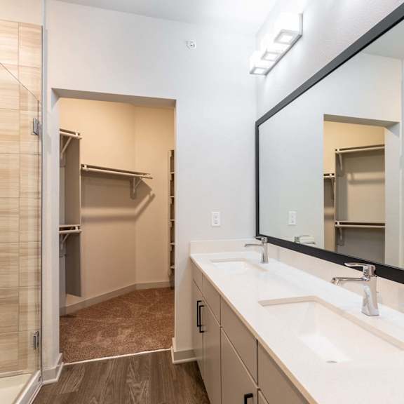 A bathroom with a walk-in shower, double sinks, and a large mirror.