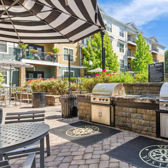 A patio with a grill and umbrella.