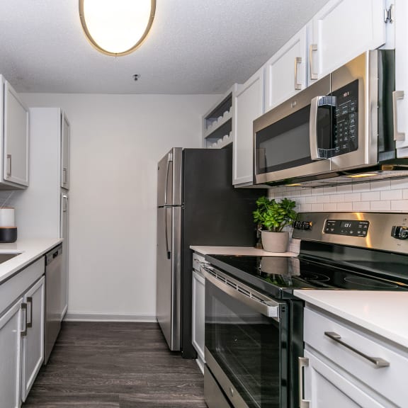 a kitchen with white cabinets and stainless steel appliances and a black stove  at Briarcliff Apartments in North Druid Hills, GA
