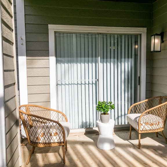 a porch with two rattan chairs and a vase with a plant at Briarcliff Apartments in North Druid Hills, Georgia, 30329