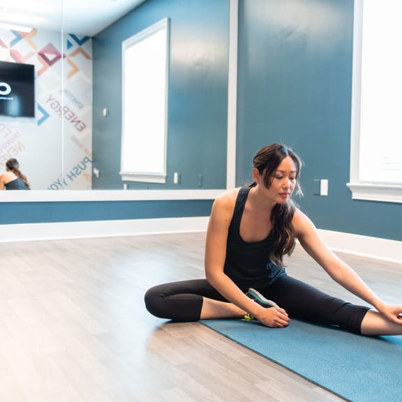 a woman sitting on a yoga mat in a yoga studio at Gwinnett Pointe in Norcross, GA 30093