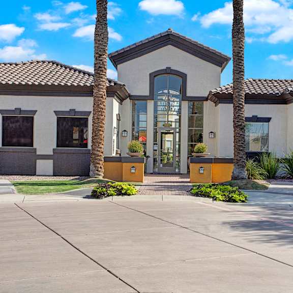 The front entrance at Sonoma Landing, a white building with brown accents, and two palm trees on either side of the entrance. 