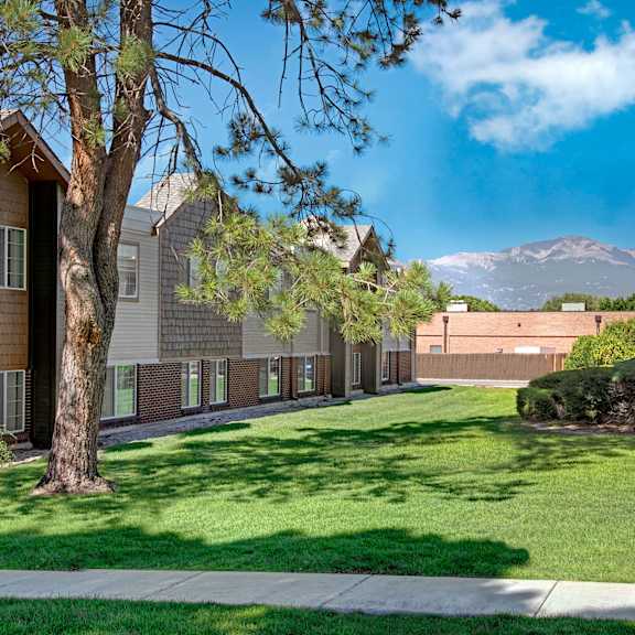 Austin Park Exterior & Mountain View Apartments with a spacious yard with green grass and trees and a mountain view at Austin Park.
