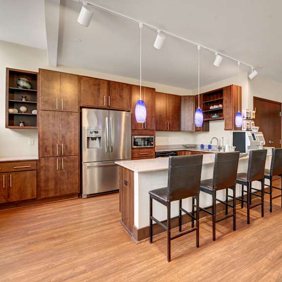 The community kitchen with stainless steel appliances, wooden cabinets, and barstool countertops. 