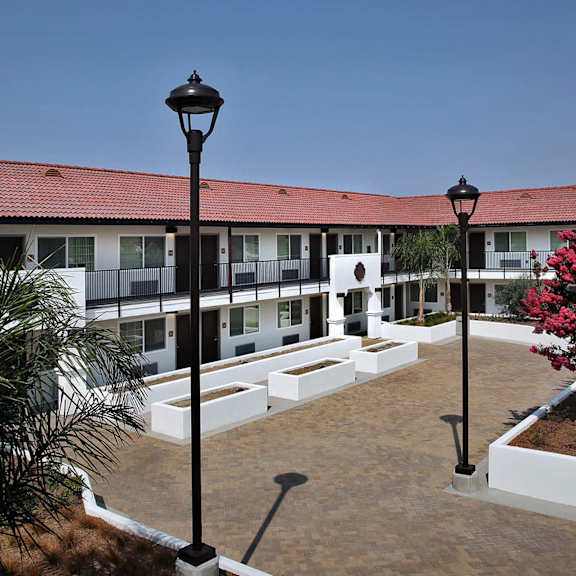 A white building with a balcony and a blue sky in the background.