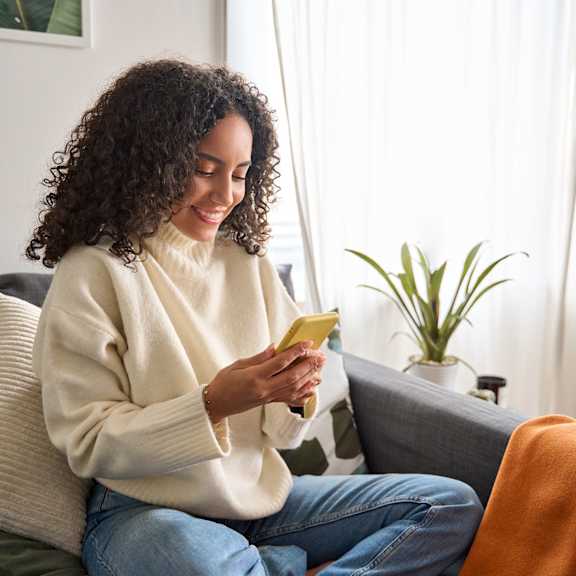 a woman sitting on a couch looking at her cell phone