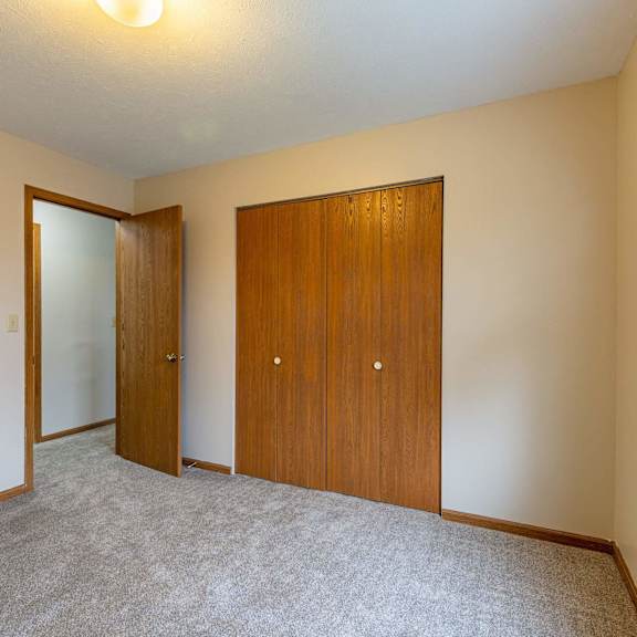 A room with a wooden floor and a kitchenette in the background.
