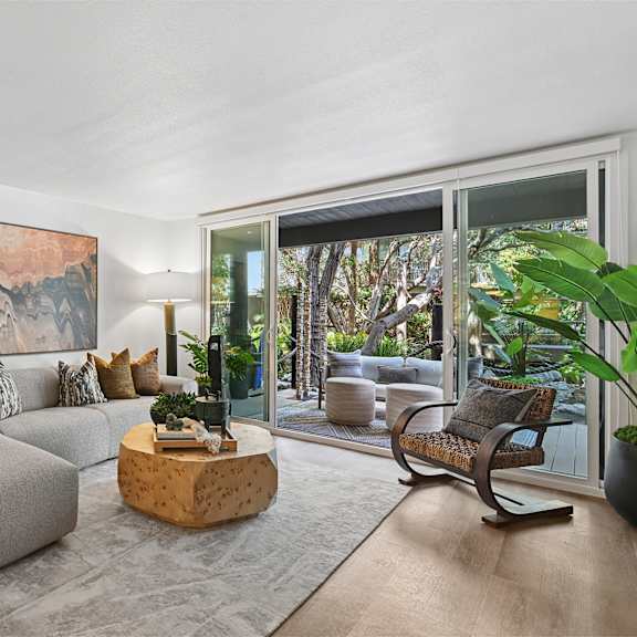 A living room with a grey couch and a large painting on the wall.