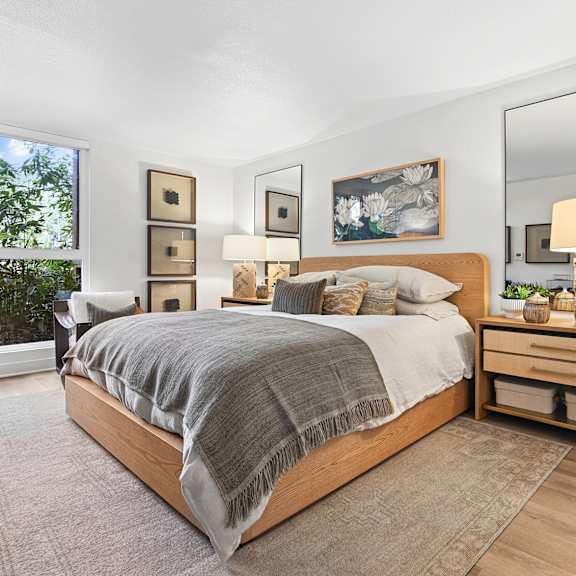 A bedroom with a large bed, a nightstand, and a mirror.